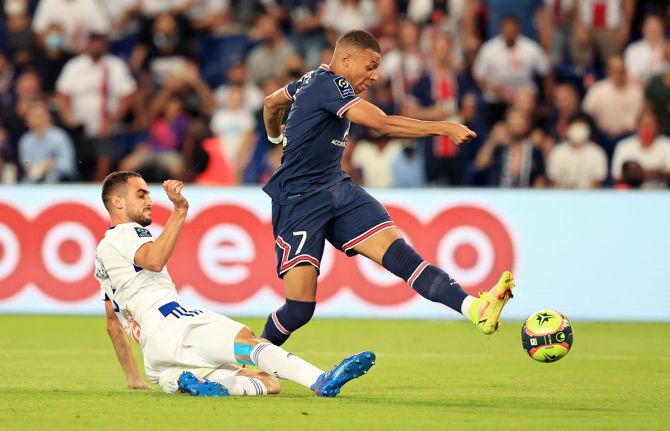 Paris Saint-Germain's Kylian Mbappe takes a shot under pressure from Lucas Perrin of RC Strasbourg Alsace during the Ligue 1 match, at Parc des Princes in Paris, France.