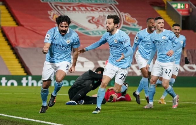 Ilkay Gundogan celebrates with teammate Bernardo Silva after scoring Manchester City's first goal during the Premier League match against Liverpool, at Anfield, on Sunday.