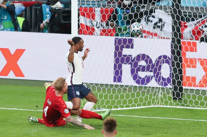 Denmark's Simon Kjaer scores an own goal while under pressure from England striker Raheem Sterling.