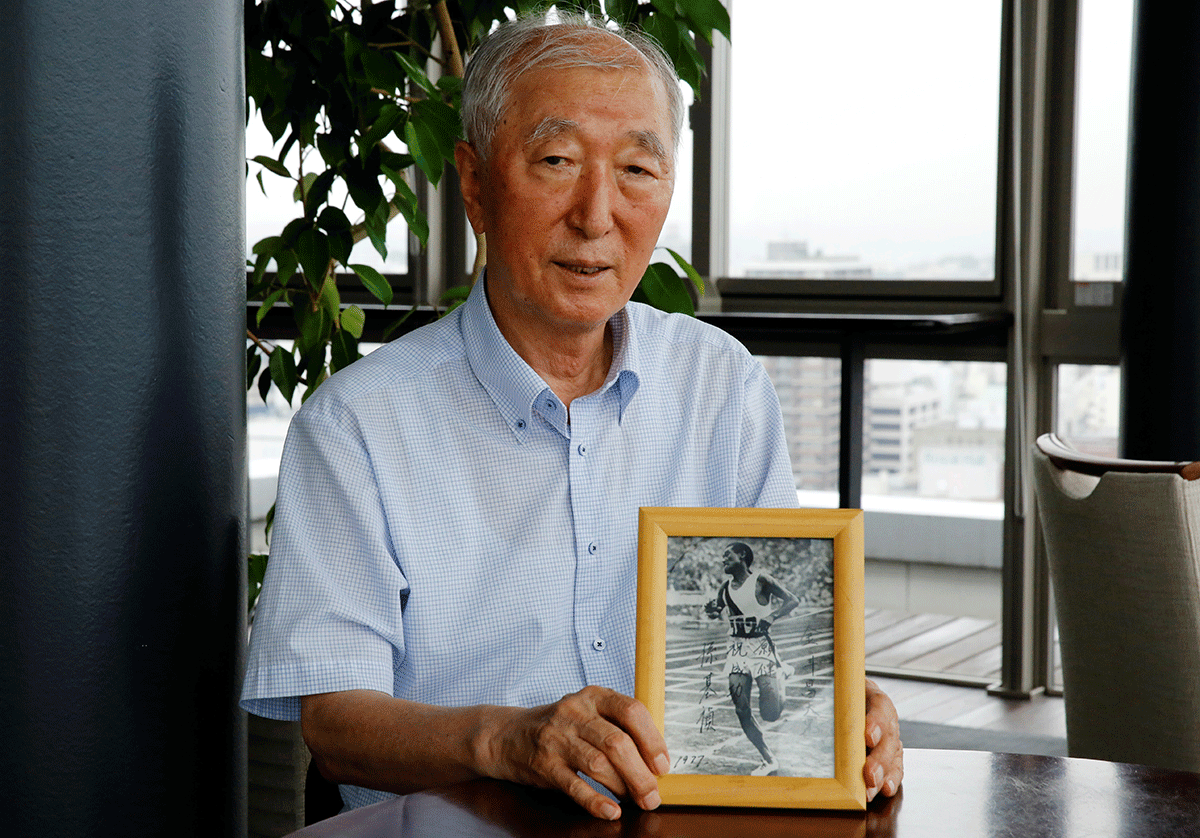Son Chung-in poses with a photograph of his father, Sohn Kee-chung, who won the 1936 Berlin Olympics marathon event