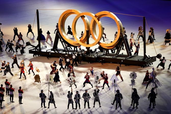 Dancers perform against the backdrop of the Olympic rings
