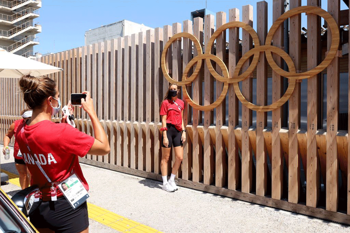 Joelle Bekhazi (left) of Canada's Waterpolo team takes a picture of her teammate Monika Eggens in front of the Olympic Rings at the Olympic Village at the Tokyo 2020 Olympic Games