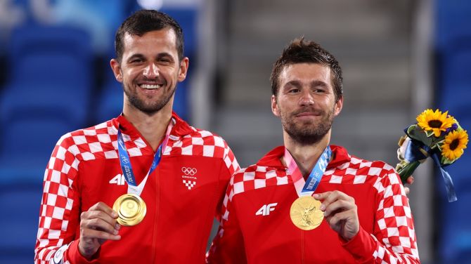 Gold medallists Mate Pavic and Nikola Mektic of Croatia celebrate on the podium. 