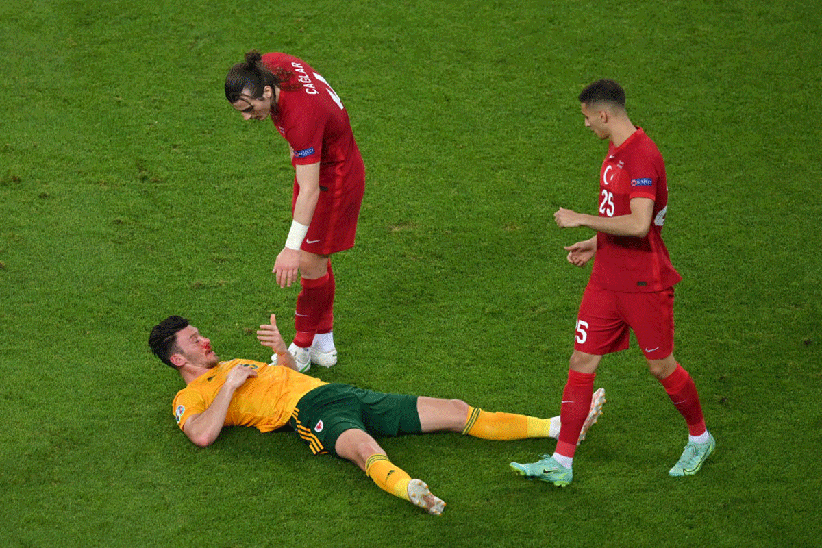 Wales' Kieffer Moore lies injured with a nose bleed as Turkey's Caglar Soyuncu checks on him