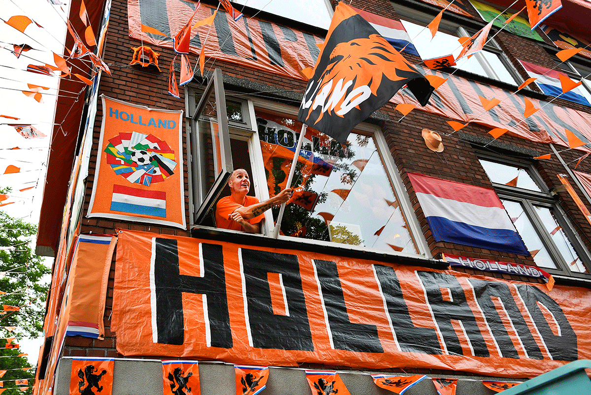 A Dutch soccer fan hangs a flag at the Marktweg that is decorated in orange for the Euro 2020 football championships, in The Hague, 