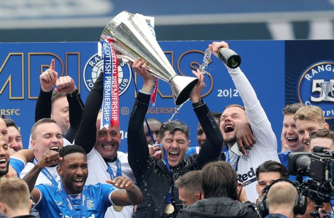 Rangers manager Steven Gerrard lifts the trophy as he celebrates winning the Scottish Premiership with assistant manager Gary McAllister, staff and players