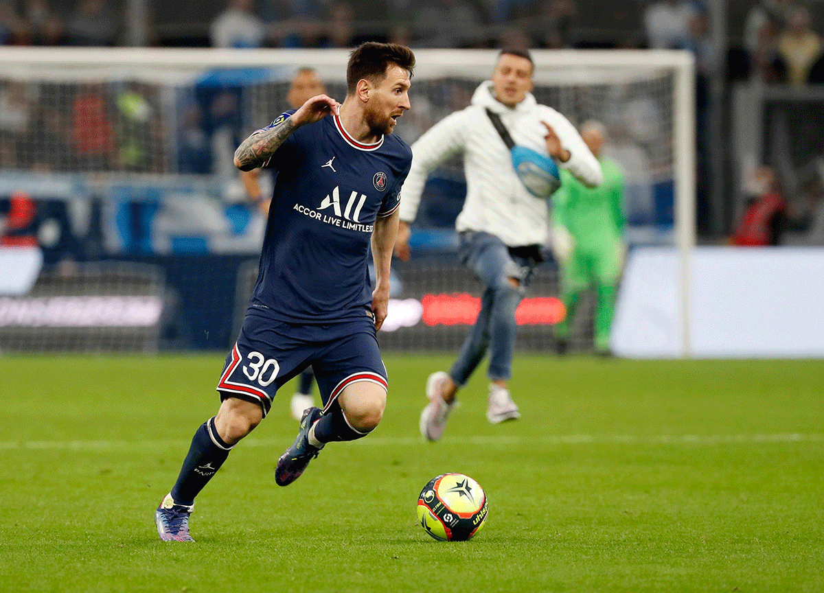 Paris St Germain's Lionel Messi in action as a fan is seen invading the pitch during the match against Olympique de Marseille at Orange Velodrome, Marseille on Sunday