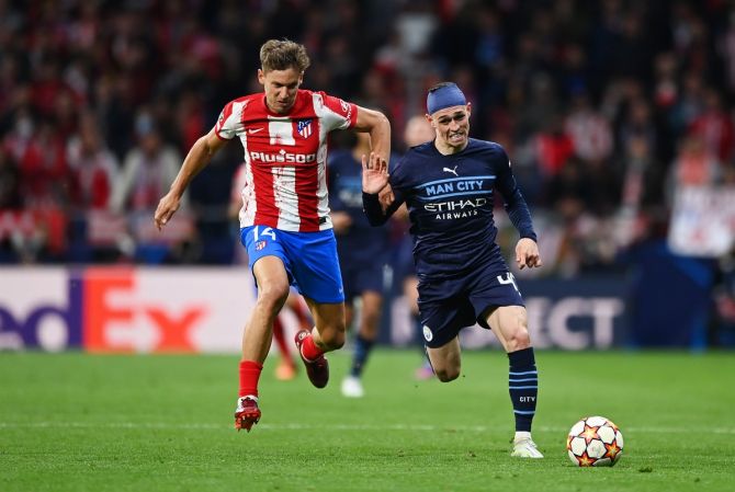 Atletico Madrid's Marcos Llorente battles for possession with Manchester City's Phil Foden.