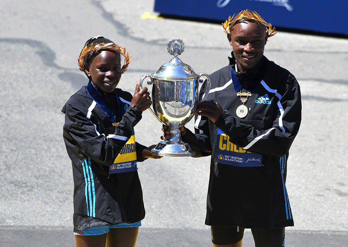 Kenya's Evans Chebet and Kenya's Peres Jepchirchir celebrate with trophy after winning the elite men's and women's race at the Boston Marathon in Boston, Massachusetts, on Monday