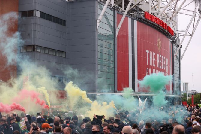 Manchester United fans with flares protest against their owners outside the stadium before the Premier League match against Liverpool at Old Trafford, Manchester, on May 13, 2021.