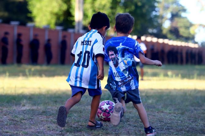 Fans wearing Lionel Messi jerseys playing football outside of the Association of Argentinian Football Headquarters ahead of the teams arrival
