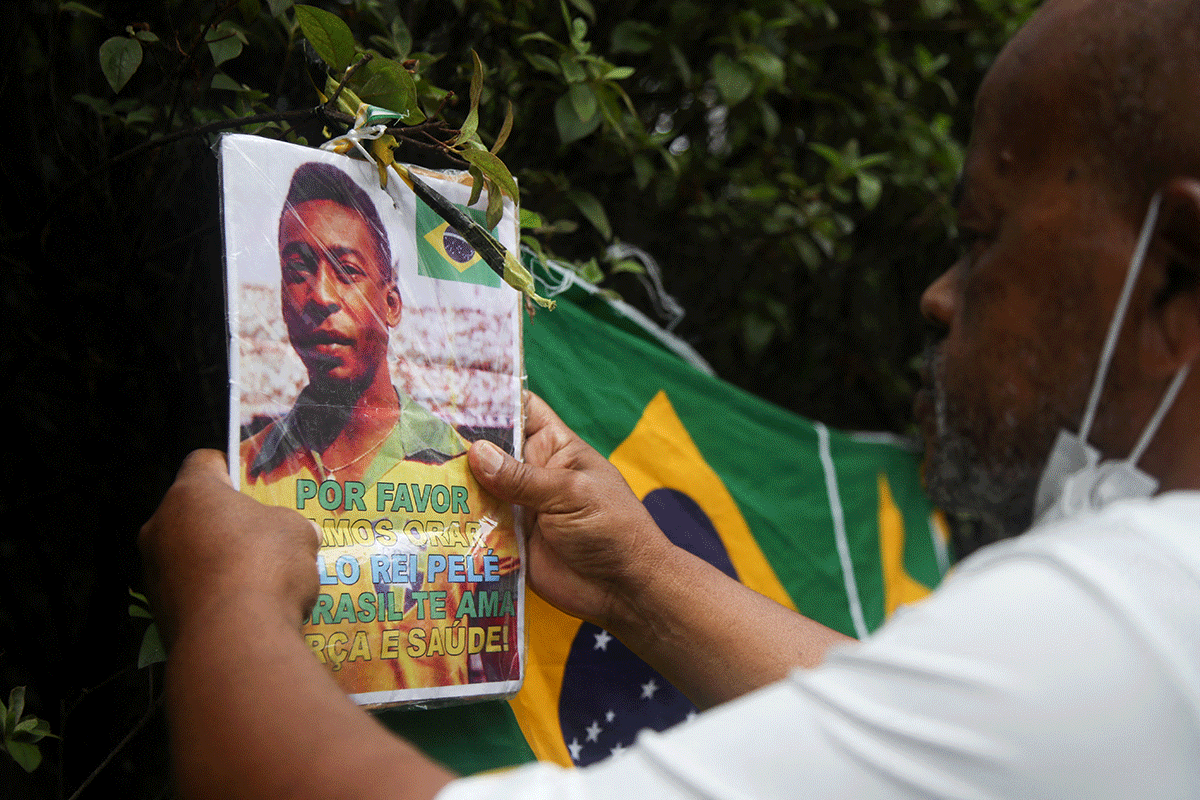 Renato Souza, a fan of Brazilian soccer legend Pele holds a placard outside the hospital as people mourn his death, in Sao Paulo, Brazil, on Friday