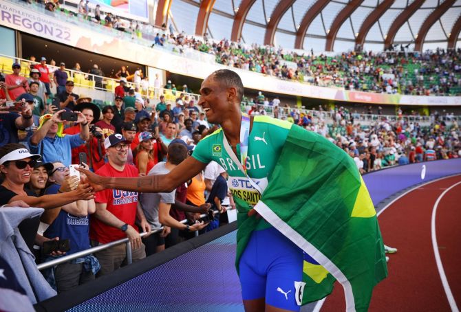 Brazil's Alison dos Santos celebrates with the flag of Brazil after winning the men's 400m hurdles.