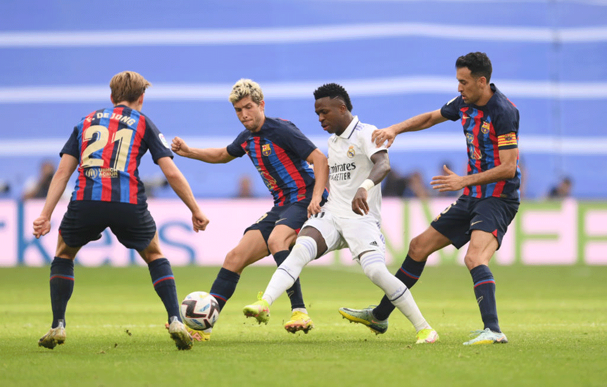 Real Madrid's Vinicius Junior is challenged by Barca's Frenkie de Jong, Sergi Roberto and Sergio Busquets. 