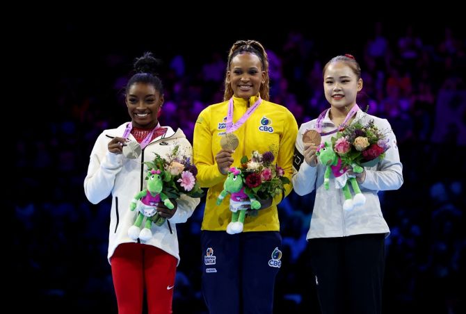 Gold medallist Rebeca Andrade on the podium alongside silver medallist Simone Biles of the United States and bronze medallist South Korea's Seojeong Yeo.