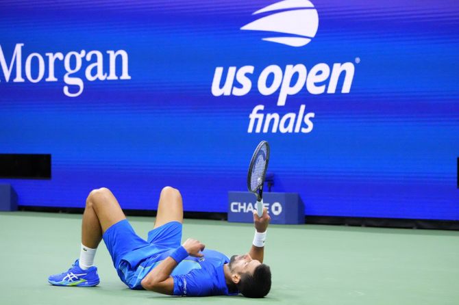 Novak Djokovic lies on the ground after losing his balance while stretching for a return.