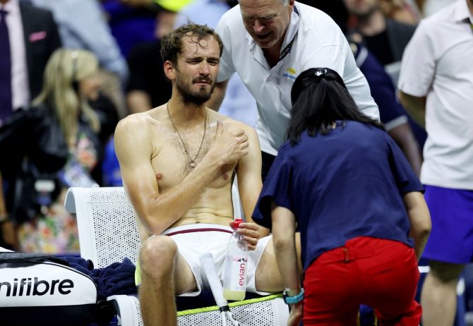 Daniil Medvedev receives medical attention after tripping over his own feet and lays sprawled across the court.