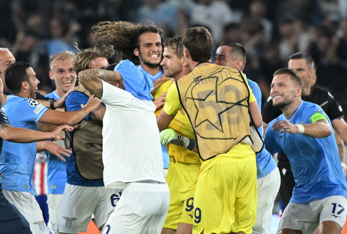 Lazio players rush to the ground to toast Ivan Provedel. 
