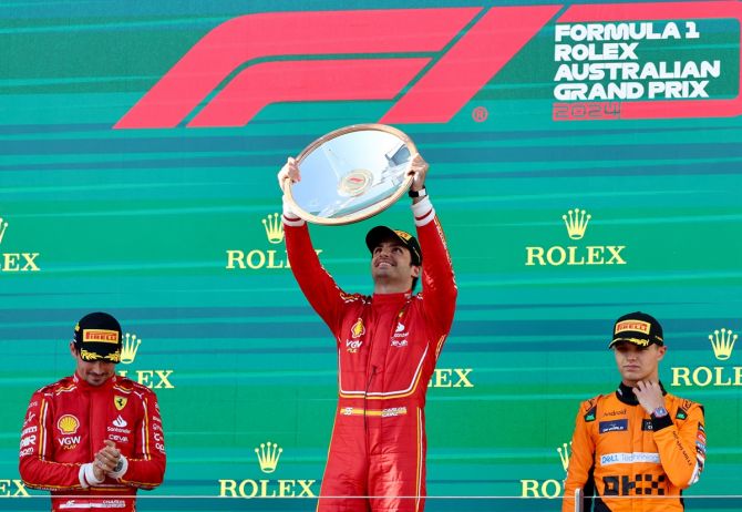Ferrari's Carlos Sainz Jr. celebrates with the trophy on the podium along with second-placed Ferrari's Charles Leclerc and third-placed McLaren's Lando Norris after winning the Australian Grand Prix, at Melbourne Grand Prix Circuit, on Sunday.