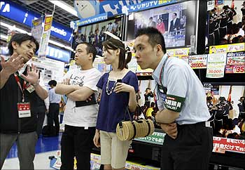 A salesman promotes television sets to visitors at an electronics shop in Tokyo.