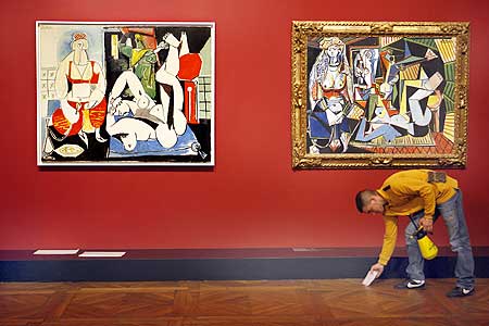 A worker cleans up at the bottom of paintings by Pablo Ruiz Picasso