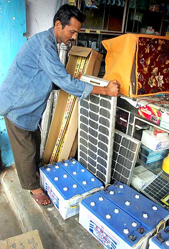 A shopkeeper adjusts a solar panel at his shop in Gosaba.