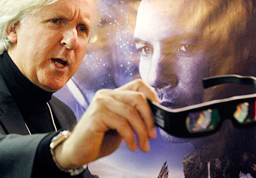 James Cameron shows 3D glasses as he poses in front of an Avatar poster