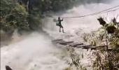 SEE: Man tries to cross raging river on wooden bridge