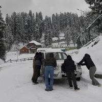 People push a car on a snow-covered road after fresh snowfall in Gulmarg/ANI Photo
