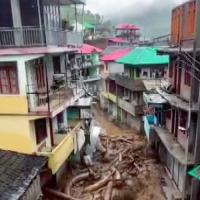 Torrential water flows down a narrow street in Mandi