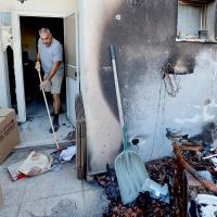 A resident clears debris in Kibbutz Beeri. Alexander Ermochenko/Reuters