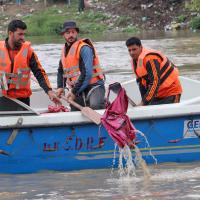 Rescuers fish out a school bag from the river. Pic: Umar Ganie