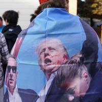 A supporter wears a cape with an image of a bleeding Trump