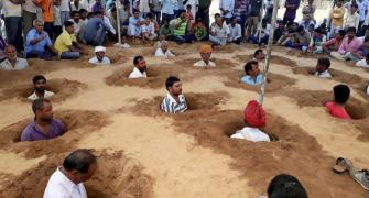 Buried neck-deep in pits, farmers protest land acquisition