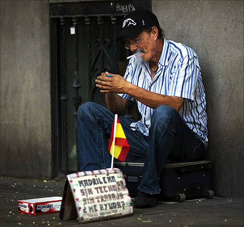 Manuel Sastre, 59, lights a cigarette as he asks for money in central Madrid.