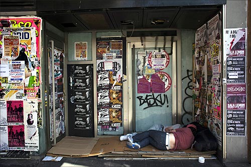 Two people sleep outside a closed down business in Madrid.