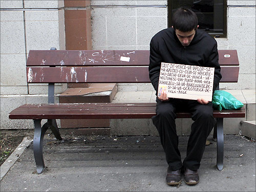 A man holds a banner as he sits on a bench in Bucharest.