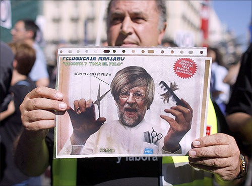 A civil service worker holds up a placard depicting a parody of Spain's Prime Minister Mariano Rajoy during a protest over government austerity measures.