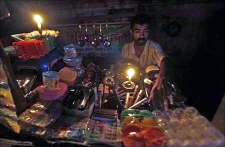 A gas oven mechanic waits for customers in his shop during a power-cut in Kolkata.