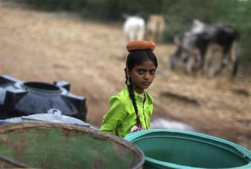 A girl stands next to the empty containers after the government-run water tanker left at Charanka village in Gujarat.