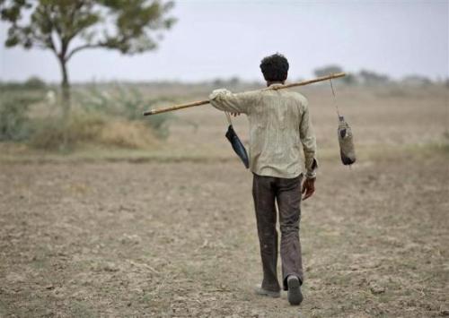 A villager carries a water bottle as he heads towards his cattle on the outskirts of Sami town in Gujarat.