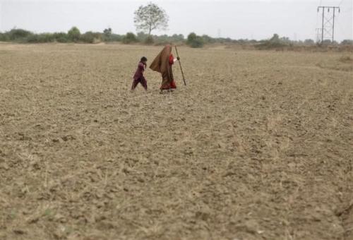 A woman walks with a boy as they migrate due to lack of water at Sami village in Gujarat.