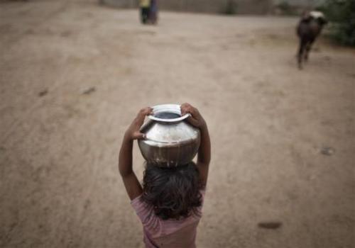 Five-year-old Joshiya, carries a metal pitcher filled with water from a near-by well at Badarganj village in Gujarat.