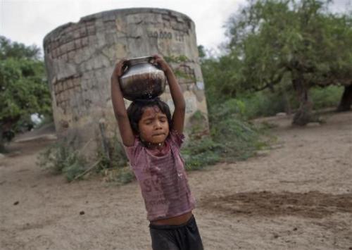 Five-year-old Joshiya carries a metal pitcher filled with water from a near-by well at Badarganj village in Gujarat.