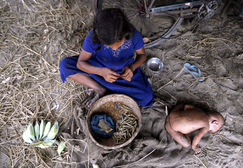 Ten-year-old labourer Toslima Khatun makes bidis (shredded tobacco hand-rolled in tendu leaves) as her seven-month-old sister Hasnuhana rests in Bhulki village.