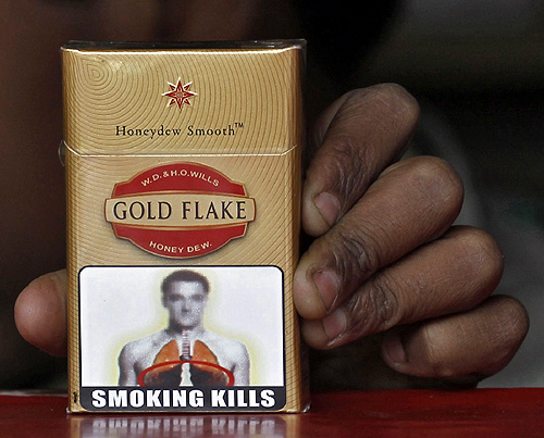 A vendor holds a cigarette pack printed with a picture bearing likeness to Chelsea's soccer player John Terry at his roadside stall in New Delhi.