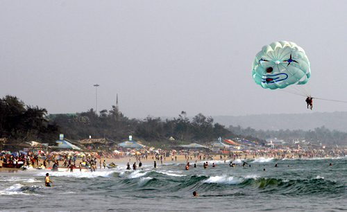 Tourists fly a paraglider over Baga beach in Goa.