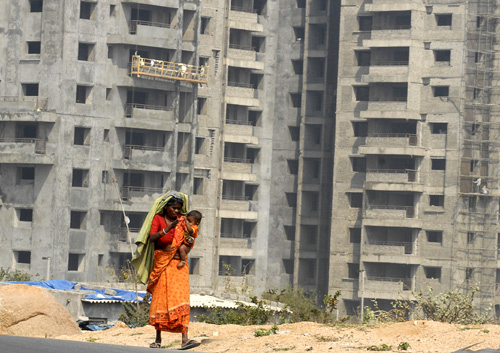 A woman carrying a child walks past a construction site for a commercial building on the outskirts of the southern Indian city of Hyderabad.