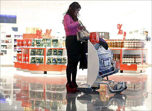 A woman from China stands with a shopping trolley in front of a Duty Free store at the Fraport airport in Frankfurt.
