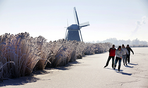 Four skaters pass a windmill as they enjoy the first time they can skate on natural ice in Zevenhuizen, near The Hague.